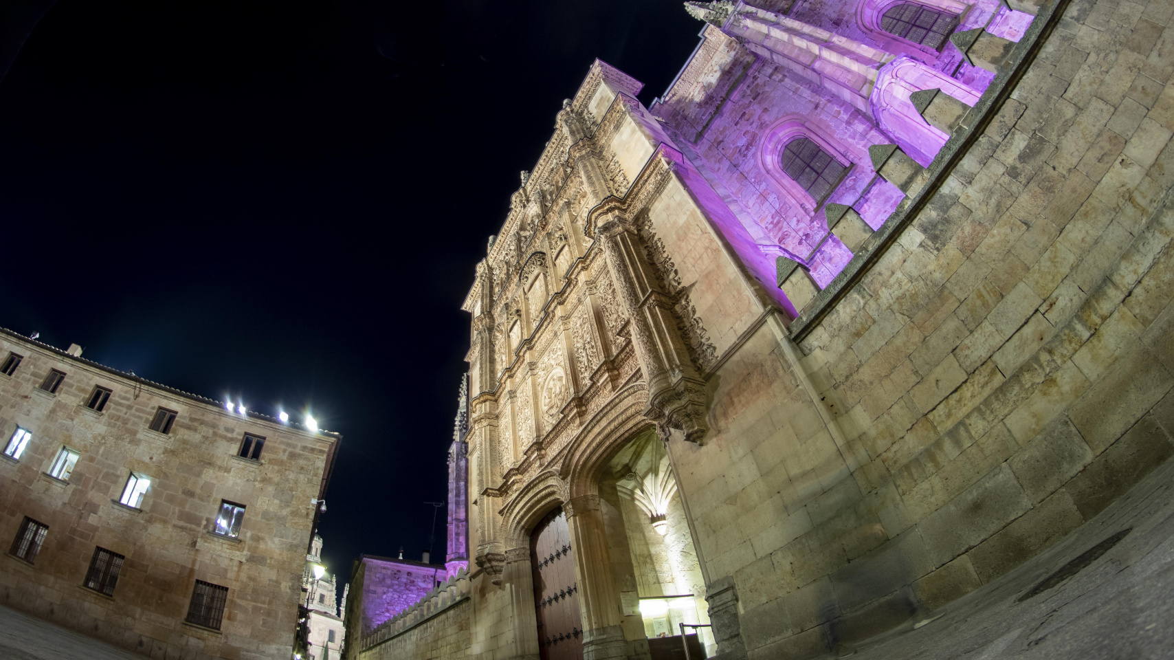 Fachada de la Universidad de Salamanca iluminada de morado