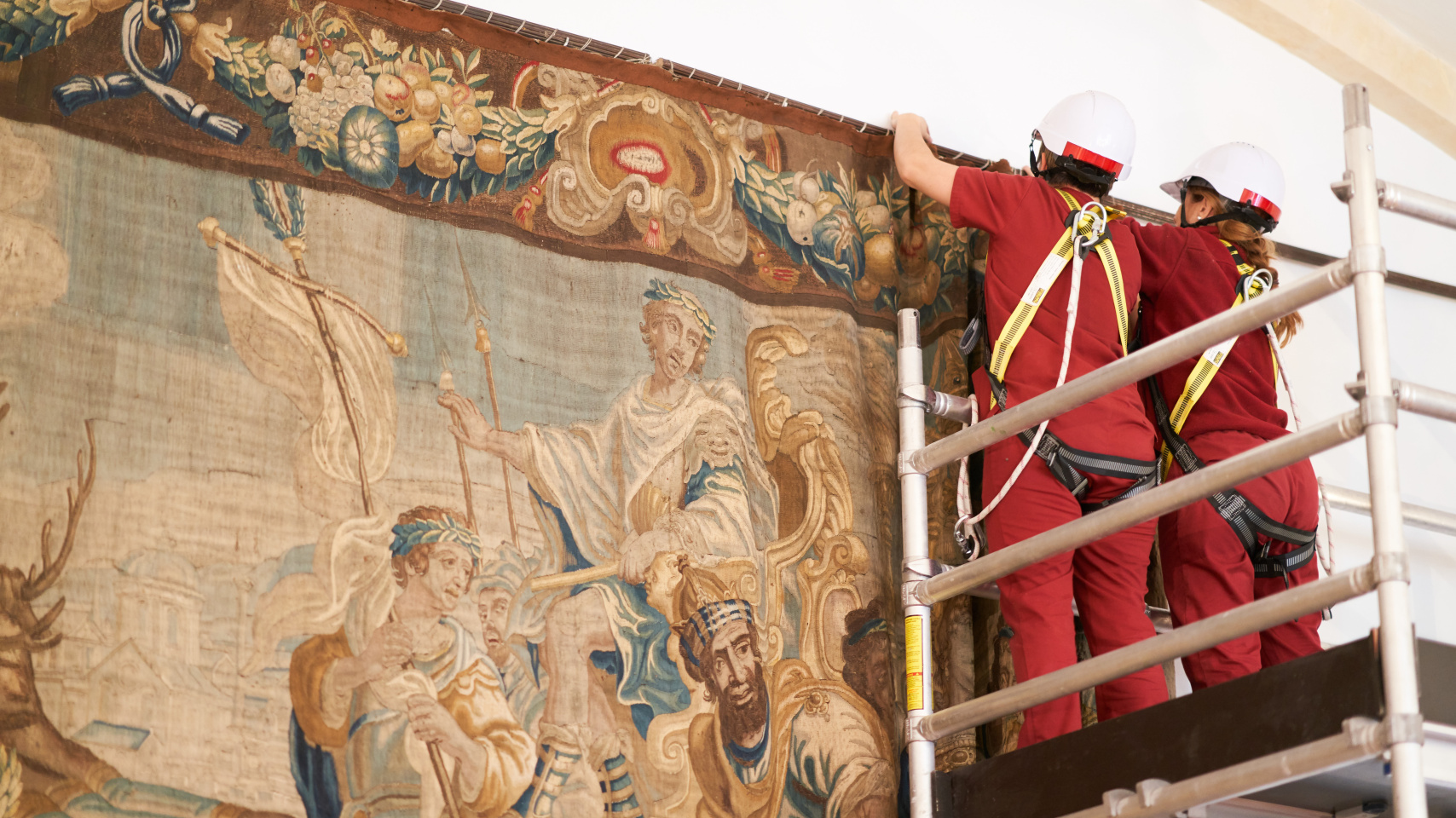 Personal de la Real Fábrica de Tapices descolgando uno de los paños flamencos de la  Universsidad