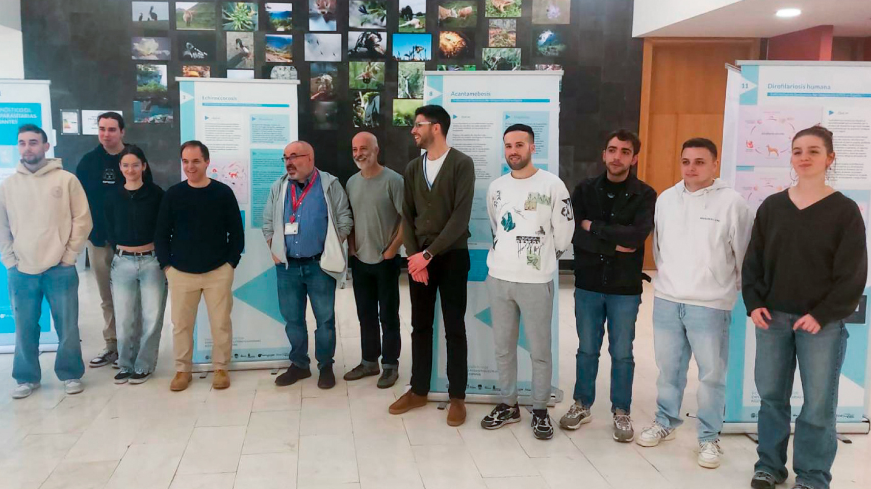 El decano de la Facultad de Biología y el autor de la exposición, junto a varios miembros del grupo de investigación 'Enfermedades Zoonósicas y Una Sola Salud' en la inauguración de la muestra