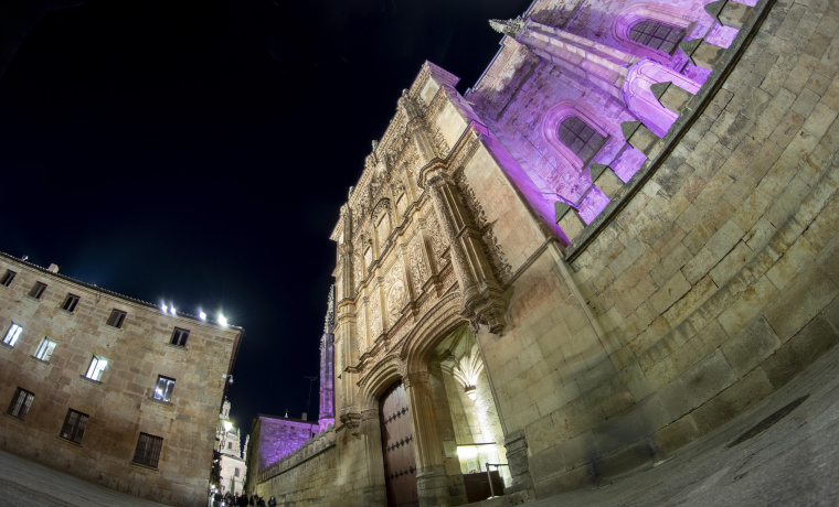 Fachada de la Universidad de Salamanca iluminada de morado