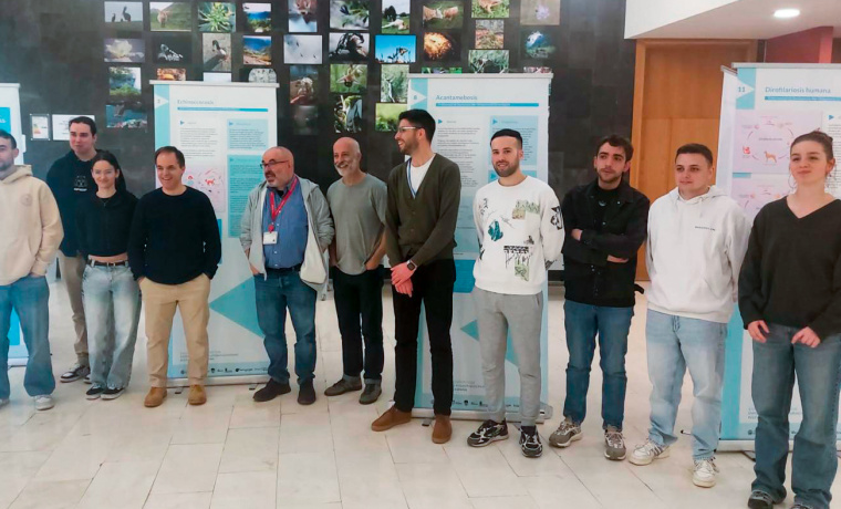 El decano de la Facultad de Biología y el autor de la exposición, junto a varios miembros del grupo de investigación 'Enfermedades Zoonósicas y Una Sola Salud' en la inauguración de la muestra