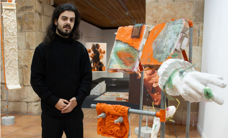 El artista Guillermo Coni Molina  posando al lado de su exposición 